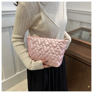 Détail d'une pochette en satin rose matelassé avec des cœurs et fermeture éclair dorée