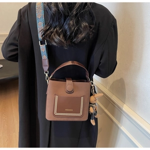 Brown PU leather bucket bag with ethnic strap and rabbit charm shown from back view