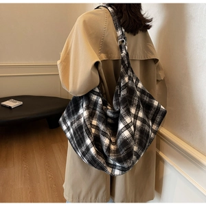Détail d'un grand sac cabas à carreaux noir et blanc porté par un mannequin en trench beige