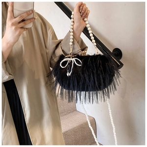 Detail of black faux feather shoulder bag featuring a beaded pearl bow and dual chains