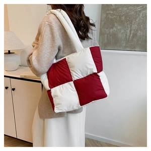 Detailed back view of a large red and white checkerboard quilted puffer tote bag on model