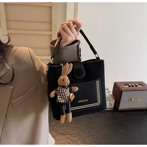 Detail of black PU leather handbag featuring metal rivets and a cute rabbit doll charm