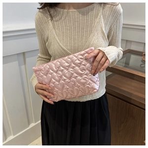 Détail d'une pochette matelassée rose en forme de cœur en tissu brillant par un mannequin