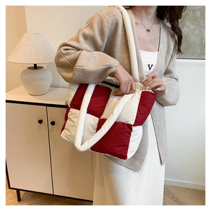 Detail of red and white checkered quilted nylon tote bag worn by a model in casual setting