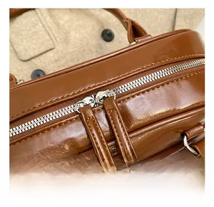 Close-up of dual silver zippers and stitching detail on a brown PU leather shoulder bag