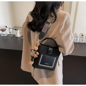Close-up of black PU bucket bag with retro patterned strap and rabbit charm detail