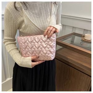 Détail d'une pochette en satin rose à surpiqûres en cœur tenue par un mannequin