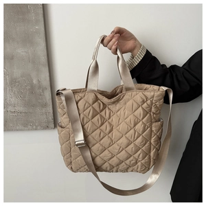 Detail der khakifarbenen Stepptasche mit Rautenmuster, Tragegriffen und Gurt