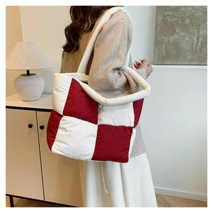 Detail of red and white checkered puffer tote bag showing quilted down fabric texture