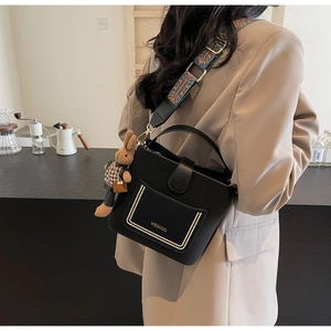 Detail of black PU leather bucket bag with floral strap and cute rabbit pendant
