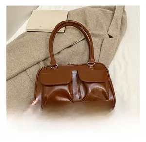 Close-up of brown PU leather shoulder bag with double flap pockets on a beige blazer