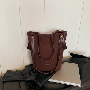 Sac seau minimaliste en daim et cuir marron foncé avec accents de clous dorés