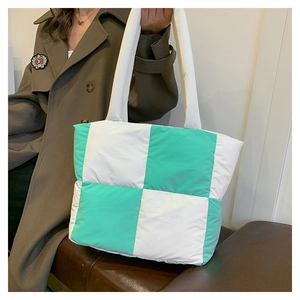 Detailed view of mint green and white checkered quilted nylon tote bag worn by a model