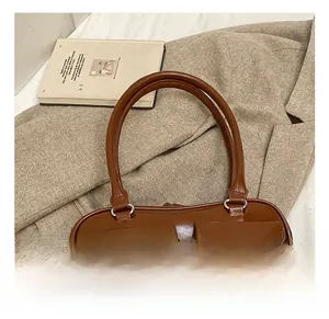 Detailed view of brown faux leather handbag with dual front pockets on beige fabric