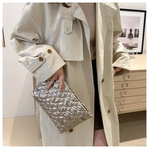 Pochette matelassée argentée métallisée portée par un mannequin en trench beige