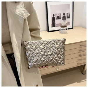 Gros plan sur la texture matelassée en forme de cœur d'une pochette métallisée champagne