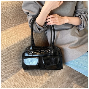 Detail of black glossy PU shoulder bag featuring dual front flap pockets and silver hardware