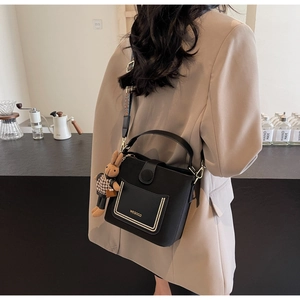 Detail of black PU leather bucket bag with decorative pocket and plush bunny charm