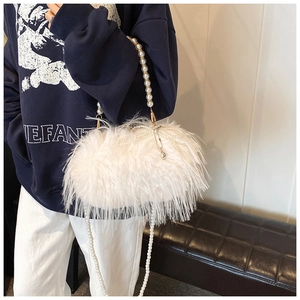 Detail of white plush shoulder bag with pearl strap and bow for women autumn style