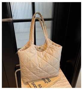 Detailed view of the beige quilted tote bag with diamond pattern stitching and dual handles