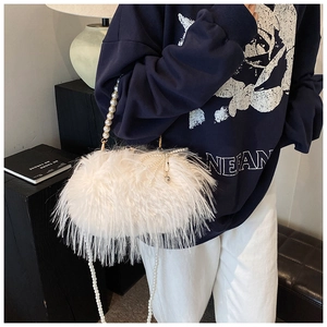 Close-up of white faux fur texture and pearl chain handle on stylish shoulder bag