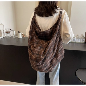 Vue arrière d'un mannequin portant un grand sac hobo en tissu à carreaux marron vintage au café