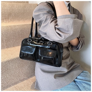 Detail of a black glossy PU shoulder bag featuring dual front flap pockets and twin straps