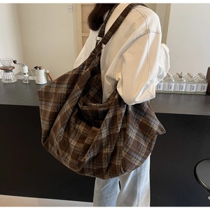 Détail d'un grand sac cabas en tissu à carreaux marron dans une scène de café au style doux