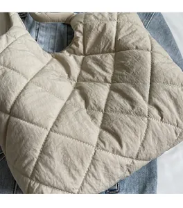 Detailed close-up of beige quilted puff shoulder bag fabric and soft diamond stitching