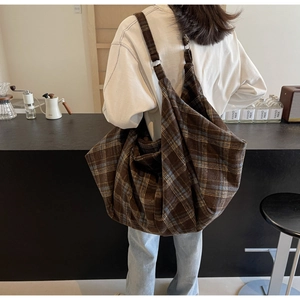 Détail du tissu à motif tartan sur un grand sac porté épaule avec sangle réglable
