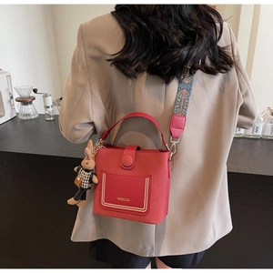 Detail of red PU leather bucket bag with wide ethnic strap and cute rabbit pendant