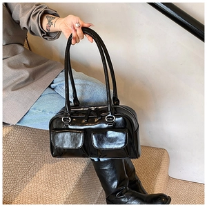 Detail of glossy black PU leather shoulder bag with silver zippers and double pockets