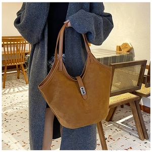 Detail of a brown suede tote bag with a metal buckle closure in a vintage cafe