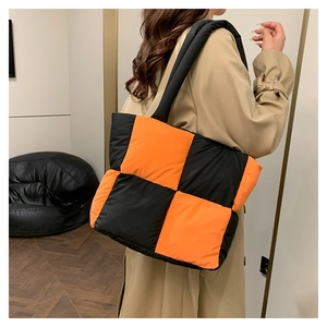 Close-up of orange and black checkerboard quilted nylon tote bag with padded texture