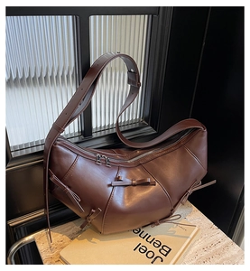 Détail du sac croissant marron foncé avec nœuds décoratifs et fermeture éclair argentée