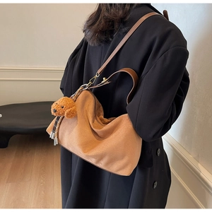 Detailed view of brown suede hobo bag featuring a cute teddy bear plush charm and leather strap