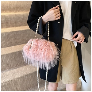 Detail of pink faux fur cloud bag featuring elegant pearl handle and crossbody strap