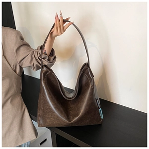 Detail of vintage dark brown PU leather shoulder bag with chic side fabric label detail