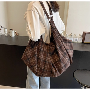 Sac hobo en toile à carreaux marron avec bandoulière réglable porté par un mannequin