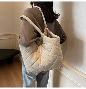 Detailed view of beige quilted tote bag showing soft puffer texture and diamond stitching
