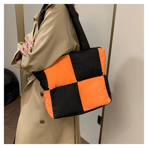 Detailed view of oversized checkered nylon tote bag worn over the shoulder by model