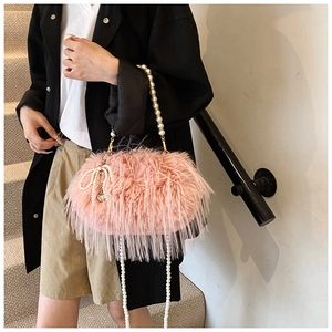 Detailed shot of pink plush faux fur bag with pearl handles and decorative bow pendant
