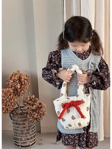 Close-up of a quilted cotton kids' handbag with brown bear prints and a red bow detail