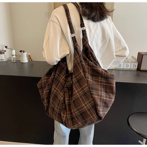 Grand sac cabas vintage en toile à carreaux porté par un mannequin dans un café chic
