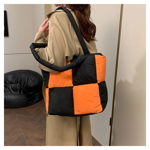 Close-up of black and orange quilted nylon tote bag with puffer texture and soft handle