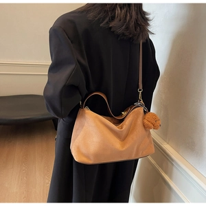 Detail view of a brown PU leather crossbody bag featuring a cute plush bear charm
