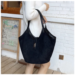 Detail of a large black suede tote bag featuring a silver metal H-shaped buckle closure