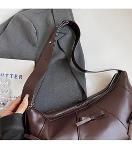 Détail du sac hobo marron vintage avec un nœud décoratif et des boucles argentées