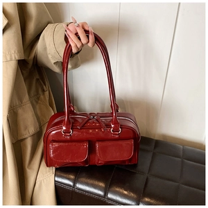 Detailed macro view of glossy burgundy PU leather handbag with dual front pockets