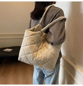 Quilted oversized shoulder bag in light beige fabric shown from a side view on model